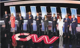  ?? Scott Olson / Getty Images ?? Sen. Michael Bennet (from left), Sen. Kirsten Gillibrand, exhousing secretary Julián Castro, Sen. Cory Booker, exVice President Joe Biden, Sen. Kamala Harris, extech executive Andrew Yang, Rep. Tulsi Gabbard, Gov. Jay Inslee and Mayor Bill De Blasio stand for the anthem.