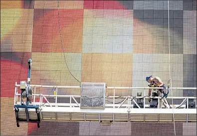  ?? AP/MARY ALTAFFER ?? A worker repairs the electric Coca-Cola billboard in New York’s Times Square in July. U.S. worker productivi­ty rose a bit more this spring than initially reported, The Labor Department said Thursday.