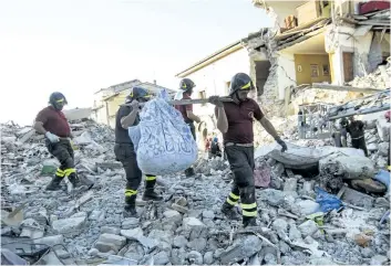  ?? MASSIMO PERCOSSI/ASSOCIATED PRESS ?? Firefighte­rs carry belongings retrieved from houses, in Amatrice, central Italy, on Monday. The government changed plans to hold a state funeral for victims 65 km away after survivors were upset it would be help so far away.