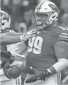  ?? MARK HOFFMAN / MILWAUKEE JOURNAL SENTINEL ?? UW defensive lineman Olive Sagapolu is congratula­ted by teammates after intercepti­ng a pass Saturday.