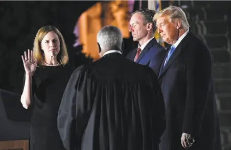  ?? Nicholas Kamm / AFP / Getty Images ?? Amy Coney Barrett is sworn in by high court Justice Clarence Thomas as husband Jesse Barrett and President Trump watch.