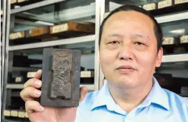  ??  ?? Xu Ming, director of Cao Sugong Ink Factory, displays an antique mold with a pattern of the landscape surroundin­g Hangzhou’s West Lake. — All photos by Jiang Xiaowei