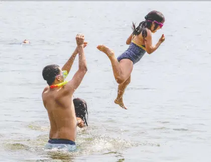  ?? JOHN MAHONEY ?? Abdel Labeche launches his sister Rama into the water while cooling off in Lac St-louis near Dorval’s Pine Beach last month.