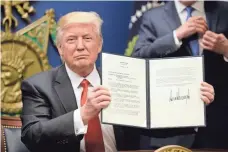  ?? POOL PHOTO BY OLIVIER DOULIERY ?? President Trump signs executive orders, including a temporary travel ban against people from seven majority-Muslim countries, at the Pentagon in Arlington, Va., on Jan. 27.