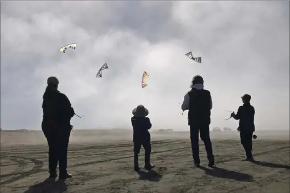  ?? P.V. NGUYEN VIA AP ?? Dylan Nguyen, from right, Scott Weider, Cardin Nguyen and Linda Marsland are shown flying kites in the fog at Long Beach, Wash.