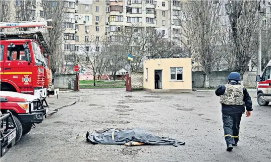  ?? ?? A man working in the fire services walks past the body of a firefighte­r who died as Russian troops shelled a station yesterday in Kherson, Ukraine, on the Orthodox Christmas Eve