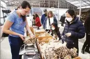  ?? ?? Carly Paterson, of Seacoast Mushroom in Mystic, helps customers during the weekly winter farmers’ market in Westport.