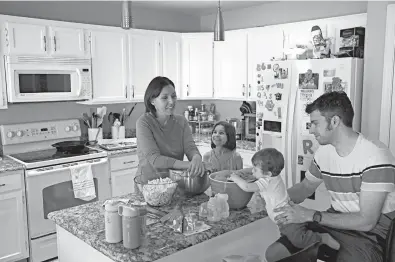  ??  ?? Katherine Rutigliano prepares a meal with her husband, Elio, along with their son, Theo, and daughter, Charlotte, at their home in Phoenix. When the couple moved away from San Francisco in 2013, they figured they would never meet a fellow Democrat again.