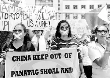  ??  ?? Filipinos hold placards outside the Chinese consulate during a protest over the reports that China would start preparatio­ns to build an environmen­tal monitoring station at the disputed South China Sea, in Makati city, Metro Manila. — Reuters photo