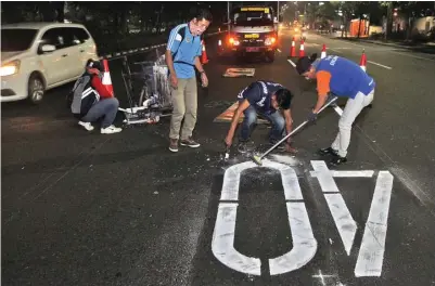  ?? HANUNG HAMBARA/JAWA POS ?? PERTEGAS PERINGATAN: Petugas dishub memperbaru­i markah batas kecepatan di frontage road Jalan Ahmad Yani Minggu malam (10/6).