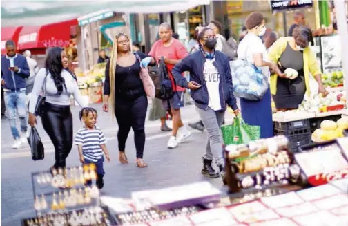  ?? Reuters ?? ↑
People shop at a market in Brixton, London, on Monday. Some of them are not wearing masks despite being ordered to do so.