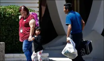  ?? AP Photo/MAtt York ?? In this July 26 file photo, a child holds the hand of a Lutheran Social Services worker as she looks back to a man as they arrive at Lutheran Social Services in Phoenix.