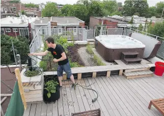  ?? JOHN KENNEY/MONTREAL GAZETTE ?? Étienne Richer wraps up a hose after tending to the garden on a rooftop deck and garden at his and Élise Boyer’s home in Montreal. They finished a deck and green roof project on top of their Villeray cottage in 2013 for about $18,000. It allows them to...