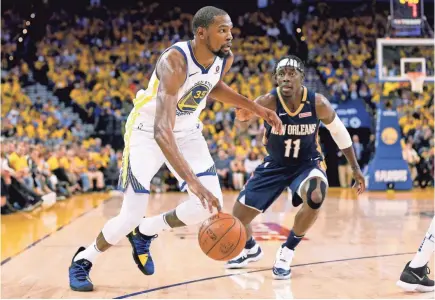  ??  ?? Warriors forward Kevin Durant, left, dominated defending Pelicans guard Jrue Holiday, right, in Game 1 of the Western Conference semifinal series.