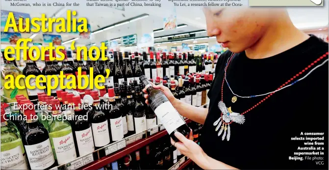  ??  ?? A consumer selects imported wine from Australia at a supermarke­t in Beijing.