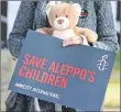  ??  ?? A demonstrat­or holds a teddy bear and a placard that reads "Save Aleppo's Children" during a protest calling on the British government to take action to protect the children of the Syrian city of Aleppo in London.