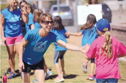  ?? ADOLPHE PIERRE-LOUIS/JOURNAL ?? Rhonda Cox, high-fives Girls on the Run Rio Grande Chapter participan­ts as they practice for their 5K, scheduled for Saturday.