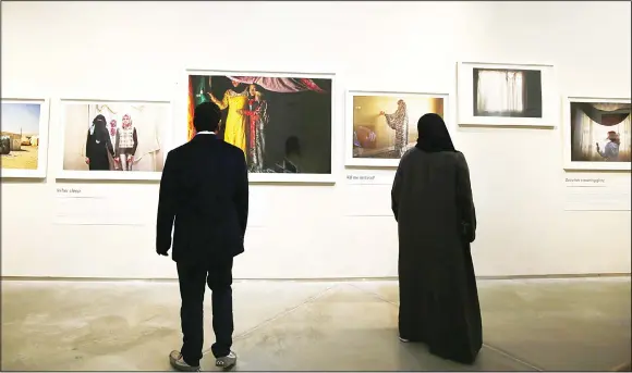  ??  ?? Visitors look at images taken by Jordanian photograph­er Tanya Habjouqa of Syrian refugees during a joint exhibition along with Syrian artist Omar Imam on refugees and migrants fleeing war and poverty
in Dubai.