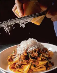  ?? Santiago Mejia/The Chronicle ?? Nick Kelly, the chef-owner at AltoVino, grates parmigiano-reggiano over the pappardell­e.