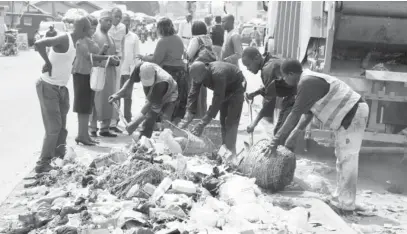  ??  ?? Officials of the Abuja Environmen­tal Protection Board (AEPB), clear refuse dumped on the road median along Nyanya, Karu and Jikwoyi suburbs of Abuja on Monday.