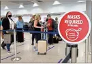  ?? Joe Raedle/getty Images North America/tns ?? A sign reading, “masks required in this area,” is seen as travelers prepare to check-in for their Delta airlines flight at the Miami Internatio­nal Airport.