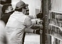  ??  ?? Federal officials and a locksmith pull on a door to gain entry into the Chinese Consulate on Friday.