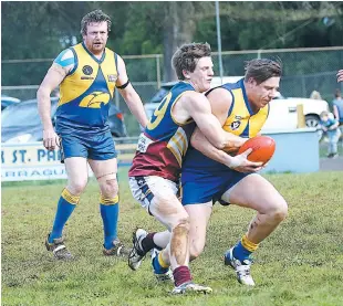  ??  ?? Ellinbank’s Matthew Barrand is wrapped up by Warragul Industrial­s player Jack O’Neil while Ellinbank’s Neale Parke watches on; Photograph­s: Tom Elton