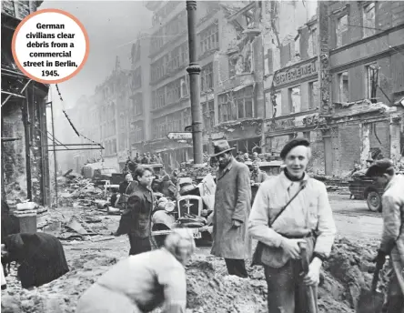  ??  ?? German civilians clear debris from a commercial street in Berlin,
1945.