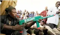  ??  ?? A member of the Yansakai vigilante group poses for a portrait with a gun inside the auditorium at the Zamfara State Government house.