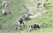  ?? KIN CHEUNG AP ?? Participan­ts compete in the downhill race at Cooper’s Hill in Brockworth, Gloucester­shire, England, on Monday.