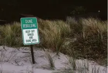  ?? ?? Left: A sign warns beach visitors about dune repair.