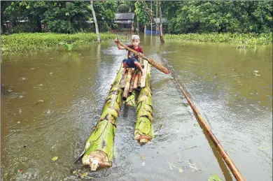  ?? ANUWAR HAZARIKA / REUTERS ?? A boy rows a makeshift raft outside his submerged house in a flood-affected village in Nagaon, India, on Tuesday.