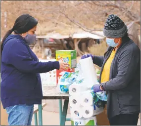  ?? (KUER/Kate Groetzinge­r) ?? Miyoshi Lee (left) and Leslie Goldtooth help residents with some basic relief goods at the center. They said joining the group has helped them find a sense of community, where they’ve both lived for over two decades.