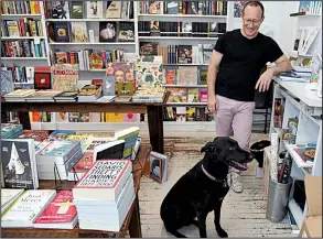  ?? TNS/Baltimore Sun/BARBARA HADDOCK TAYLOR ?? Dr. John Krakauer of Baltimore, a regular customer, waits at the register with Audie, the store owner’s dog, at Greedy Reads in Fells Point, Md.