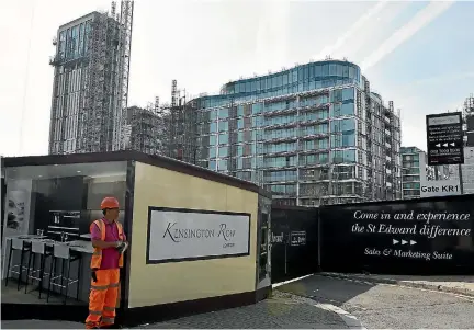  ?? PHOTO: REUTERS ?? A worker stands outside a new housing developmen­t in the upmarket London district of Kensington where 68 apartments have been assigned to rehouse families who lost their homes in the Grenfell Tower fire.