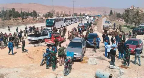  ?? AP ?? ■ Syrian regime forces gather next to buses meant to carry rebels and their families, at a checkpoint in eastern Ghouta yesterday. They were expected to leave a besieged town in the eastern Ghouta suburbs of Damascus in an evacuation deal.