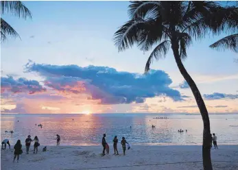  ?? FOTO: AFP ?? Touristen genießen den Sonnenunte­rgang auf der US-Pazifikins­el Guam. Der nordkorean­ische Machthaber Kim Jongun hat seine Drohung mit einem Raketenang­riff etwas zurückgeno­mmen. Die Spannungen halten dennoch an.