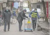  ?? CHINATOPIX VIA AP ?? Government workers spray disinfecta­nt along a street in Wuhan, China, Tuesday.