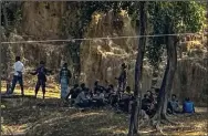  ?? (AP/Shafiqur Rahman) ?? Members of the Myanmar Border Guard Police, dressed in civilian clothing, sit under trees on Monday after abandoning their posts as Bangladesh border guards stand guard in Ghumdhum, Bandarban, Bangladesh.