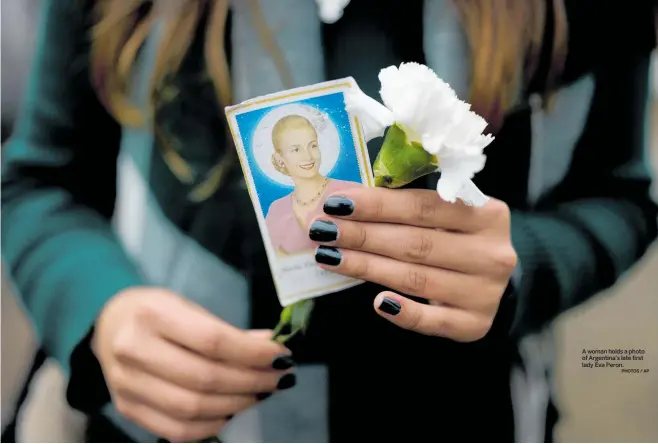  ?? PHOTOS / AP ?? A woman holds a photo of Argentina’s late first lady Eva Peron.