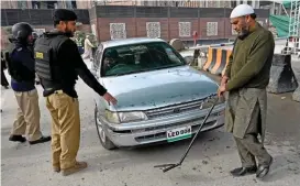  ?? (AFP) ?? Policemen search a car before it enters a police compound in Peshawar on Wednesday