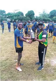  ?? CONTRIBUTE­D ?? Jamaica Rugby Football Union (JRFU) Chairman Jerry Benzwick (right) hands the JRFU Men’s 15s Championsh­ip trophy to Jamaica Defence Force Warriors captain Hubert Thomas after their 21-17 win over the Mona Titans in Saturday’s grand final.