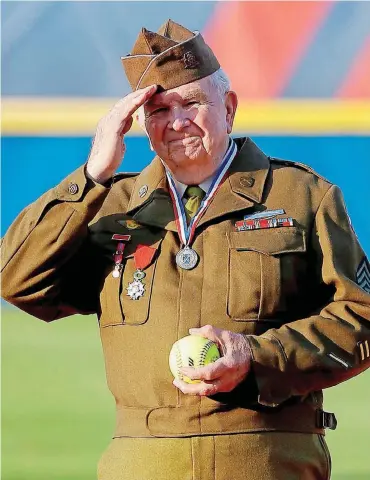  ?? [PHOTO BY BRYAN TERRY, THE OKLAHOMAN] ?? World War II veteran Harley Richardson salutes the World Cup of Softball crowd before throwing out the first pitch at the United States and Japan game in Oklahoma City on Friday.