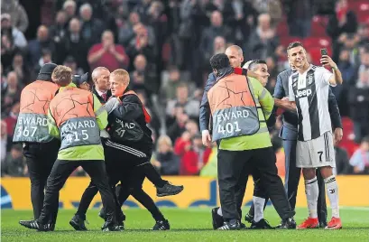  ?? LAURENCE GRIFFITHS GETTY IMAGES ?? Cristiano Ronaldo of Juventus takes a selfie with a pitch invader after his team’s 1-0 Champions League win at Manchester United.