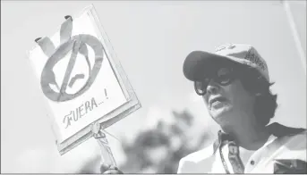  ??  ?? An opposition supporter holds a sign that reads “Out” as she gathers to rally against Venezuelan President Nicolas Maduro’s government at the ColombianV­enezuelan border over the Simon Bolivar internatio­nal bridge, on the outskirts of Cucuta, Colombia February 15, 2019. REUTERS/Edgard Garrido