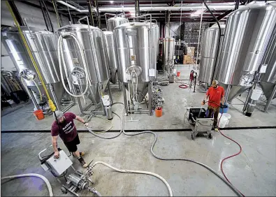  ?? NWA Democrat-Gazette/CHARLIE KAIJO ?? Brewers Brock Carson (left) and Brant Bishop work last month at Ozark Beer Co. in Rogers.