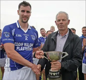  ??  ?? Toss Ryan presents the cup to Our Lady’s Island captain Fintan Mullins after his side’s victory over St Mary’s (Rosslare) in the final in Kilmore. s