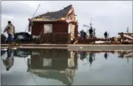  ?? BRANDEN CAMP — THE ASSOCIATED PRESS ?? People are reflected in a swimming pool as they work to clean up at a home that was damaged by a tornado Sunday in Adel, Ga.