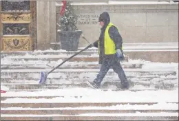  ?? H John Voorhees III / Hearst Connecticu­t Media ?? Fernando Barzoza clears snow from the steps of the Savings Bank of Danbury building on Main Street in Danbury in February 2021.