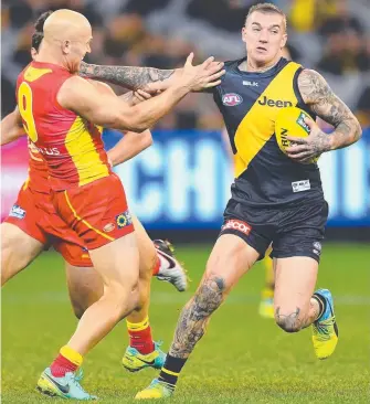  ??  ?? Tigers superstar Dustin Martin (right) fends off a tackle from Suns midfield maestro Gary Ablett.